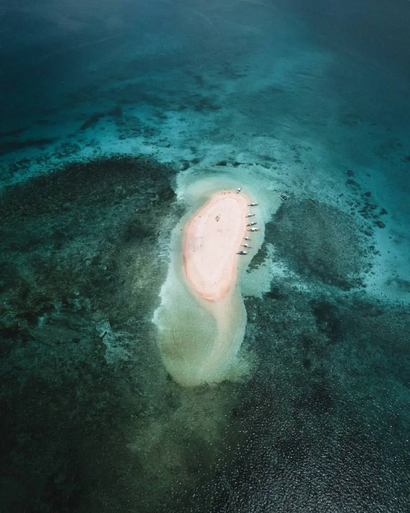 An aerial view of a pink island in the ocean.